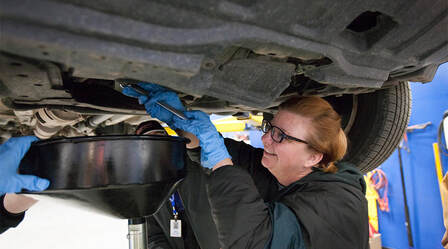 Woman working on the underside of a car